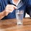 Close up on man right after dropping an antacid tablet in a glass of water