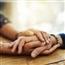 People comforting one another (picture shows close up on their clasped hands on a table)