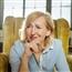 Female therapist sitting in armchair leaning forward with hand under chin with look of intense scrutiny on her face