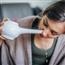 Young woman holding neti pot to nose for nasal irrigation