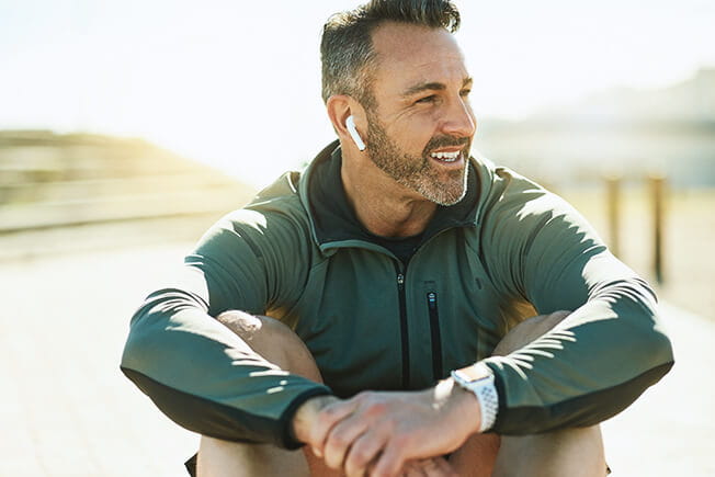 Shot of a mature man using wireless earphones while out for his workout