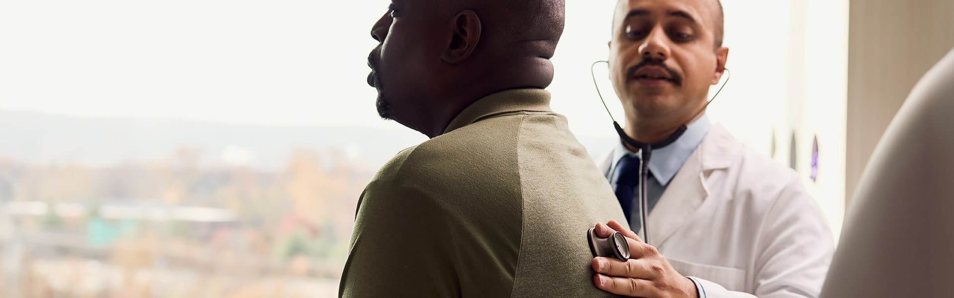 Doctor listening to patients lungs with stethoscope